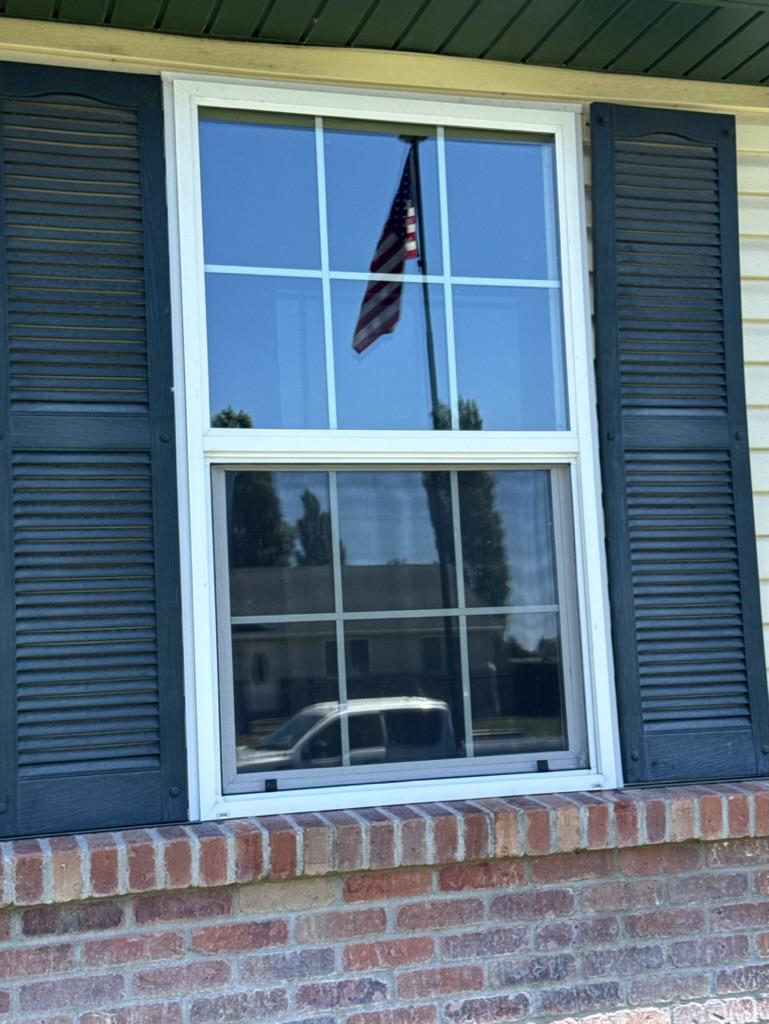 Crystal-clear window cleaned by TrueClear reflecting an American flag and blue sky in Idaho Falls